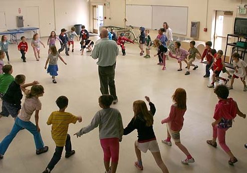 man calling a dance to a circle of children