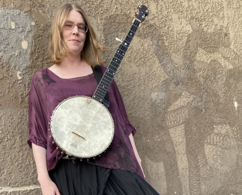 woman wearing a banjo leaning against a wall