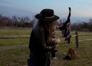 a woman in a hat, a person flipping over a fence, a dog