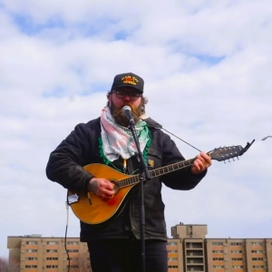 man on a roof playing a bouzouki or maybe a cittern