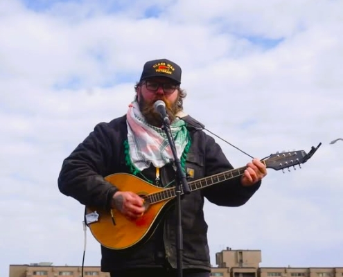 man on a roof playing a bouzouki or maybe a cittern